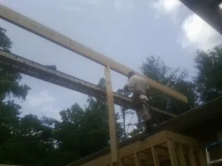 Carpenter setting a ridge beam over a new addition frame — Ice Dam Removal by Roofing Brothers in Elyria