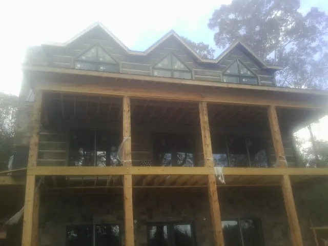 Dormers and porch framing on a large log home under construction — Roof Coating work by our crew in Elyria