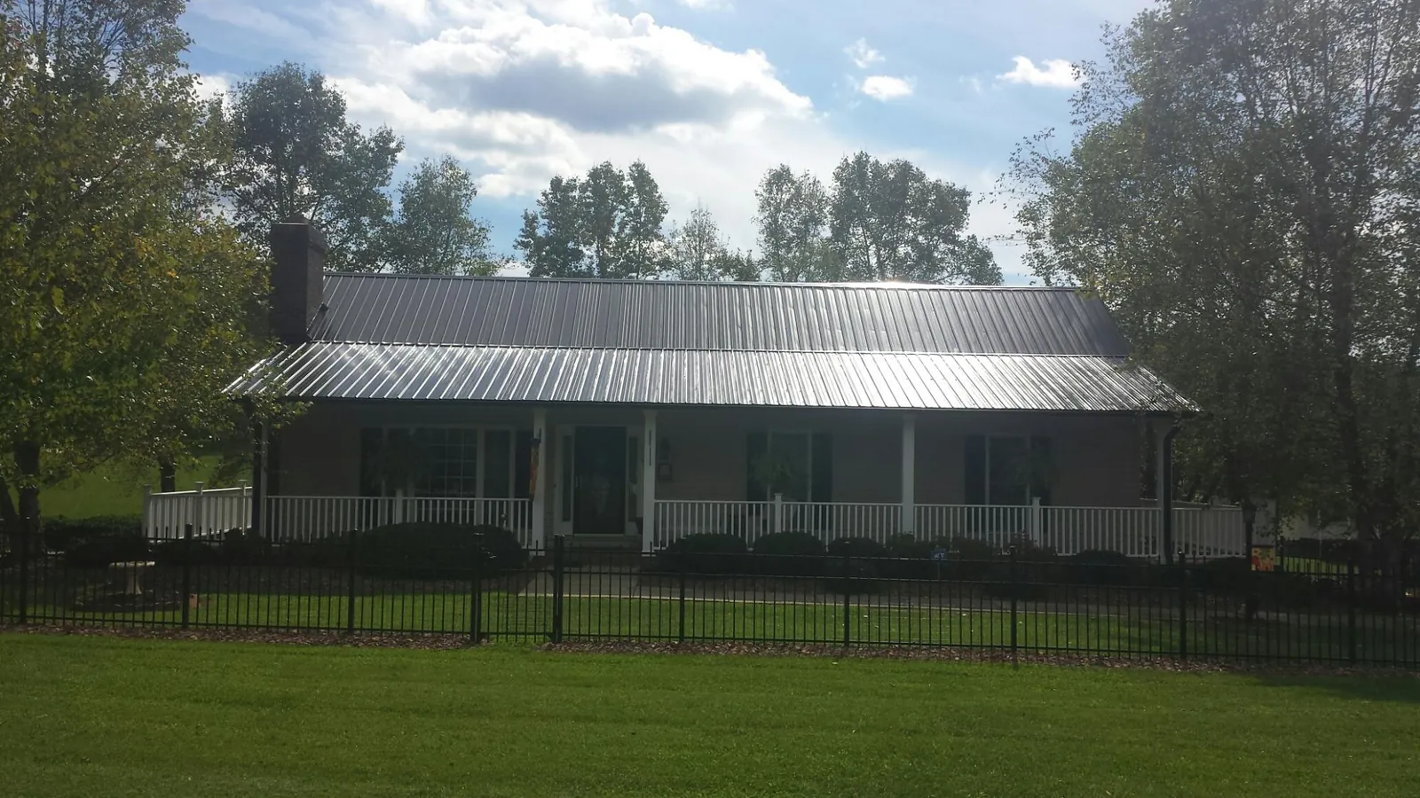 Gray metal roof on a brick ranch with a full width front porch — Gutter Guard Installation work by our crew in Elyria
