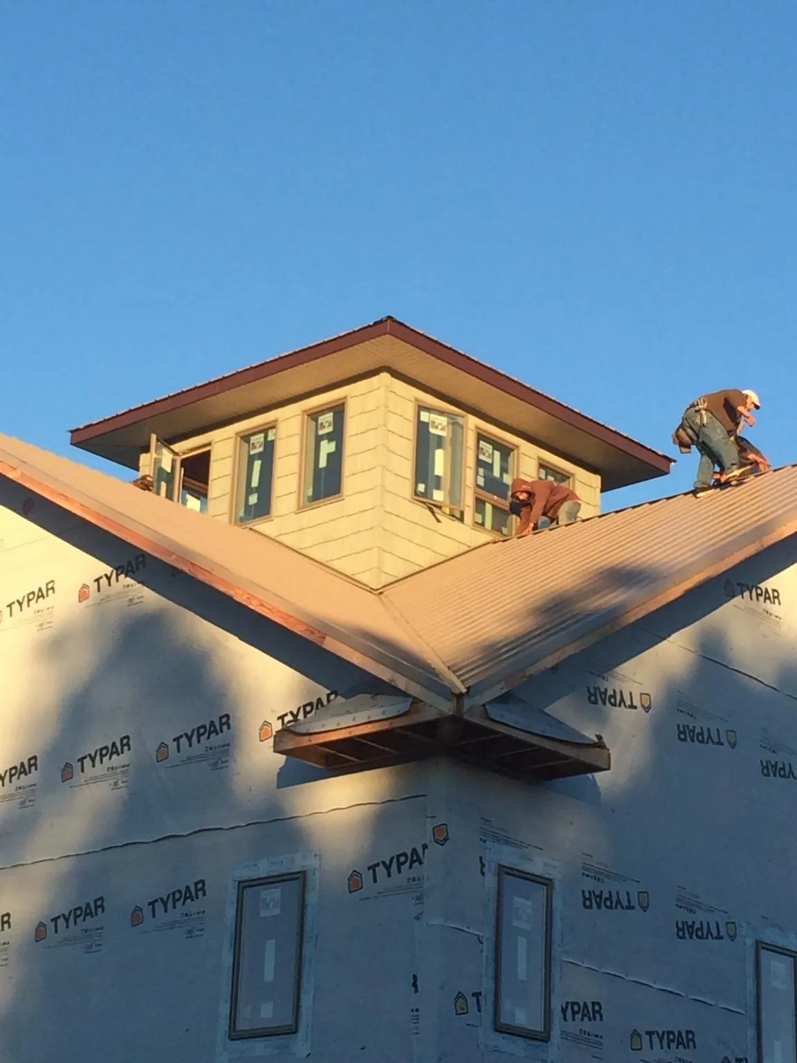 Roofers working around a rooftop cupola on a new metal roof at sunset — Roof Waterproofing in Elyria by Roofing Brothers